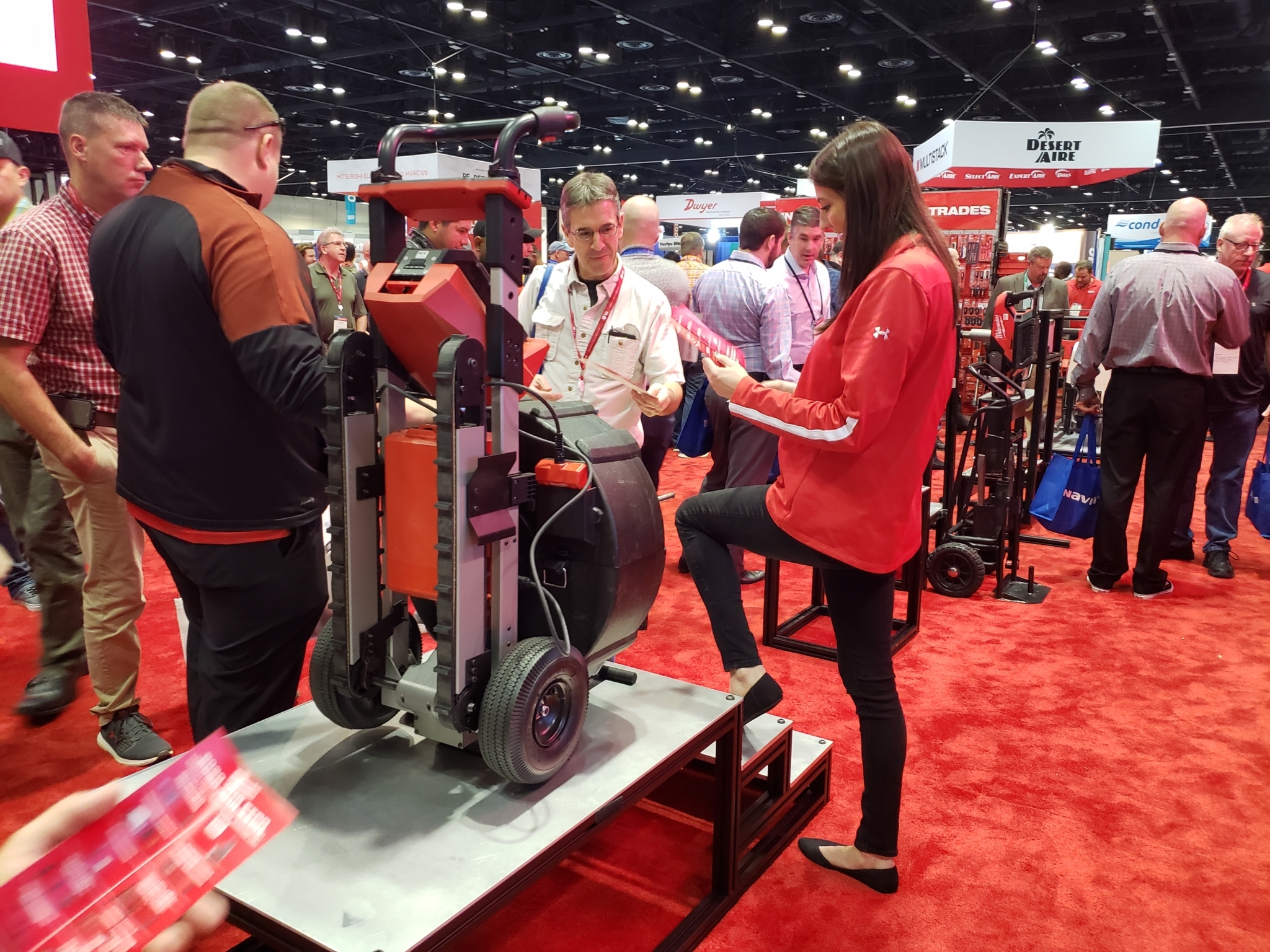 A Milwaukee Tool representative shows AHR Expo attendees the new MX FUEL drum drain cleaning machine, which has a built-in stair climber.